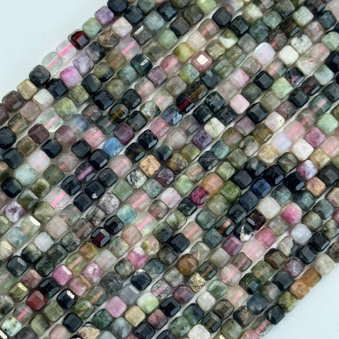 Beads in strand with multiple color from pink and green beads to black and yellow in cube or square shape