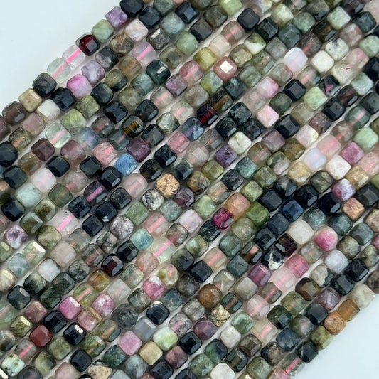 Beads in strand with multiple color from pink and green beads to black and yellow in cube or square shape
