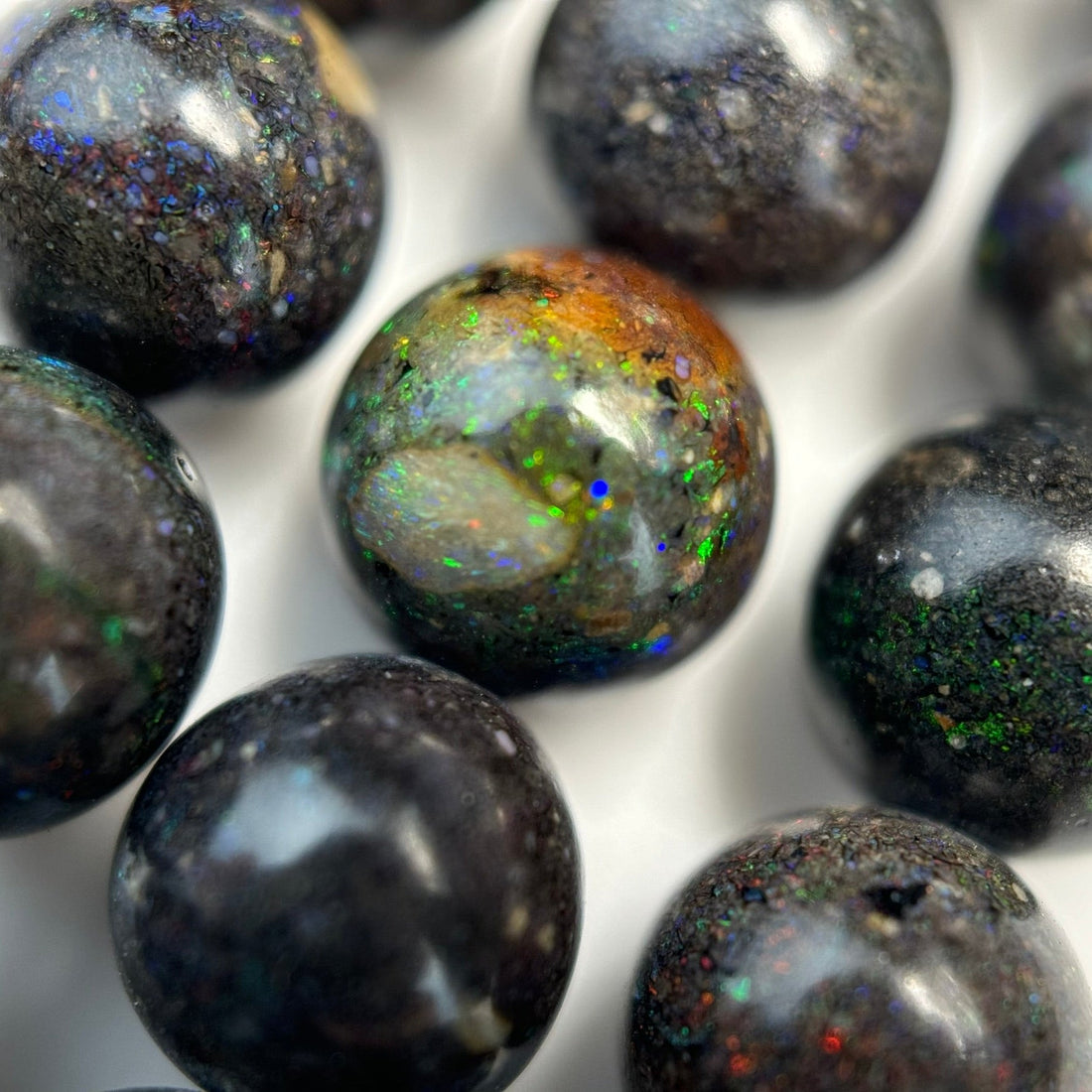 Natural Black Opal Polished Round Beads arranged on a gemstone strand for bracelet and jewelry making.