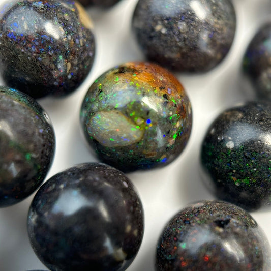 Natural Black Opal Polished Round Beads arranged on a gemstone strand for bracelet and jewelry making.