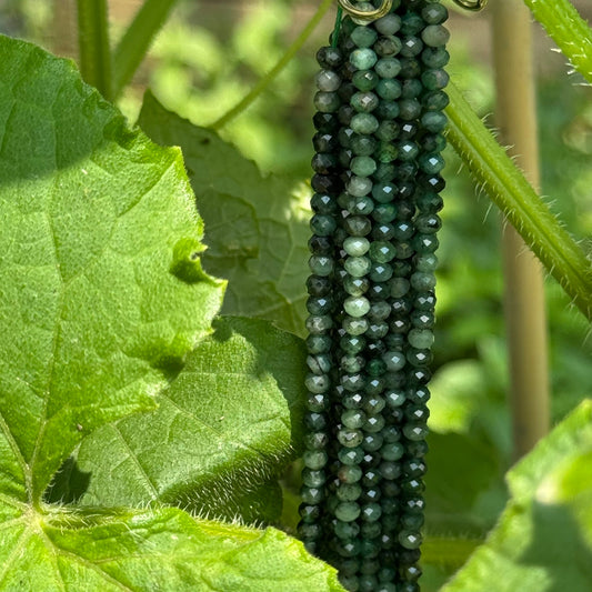 AAA quality natural Emerald Rondelle Beads with faceted surfaces arranged on a strand for handmade jewelry making.
