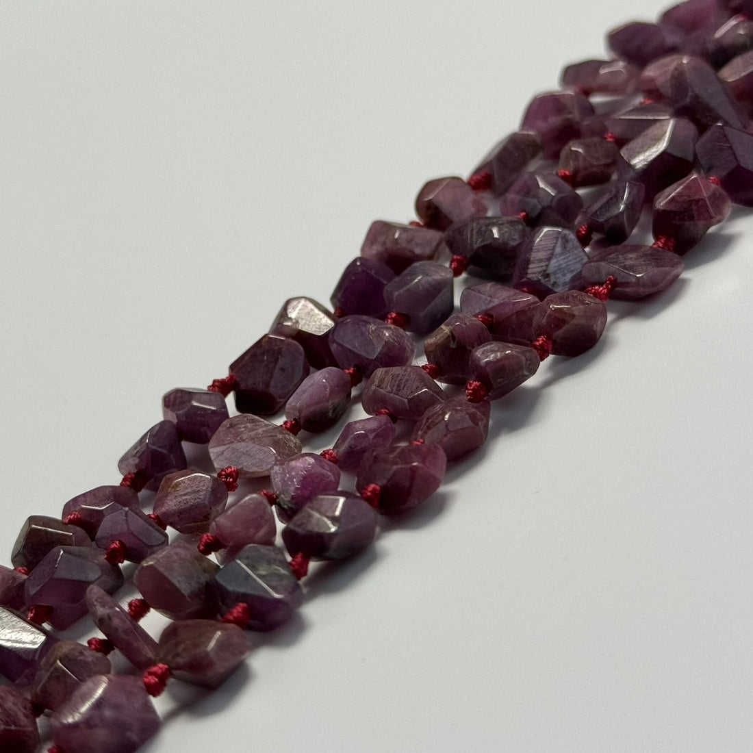 Natural red ruby compared with laboratory-grown, treated, and imitation ruby gemstones during gemological examination.