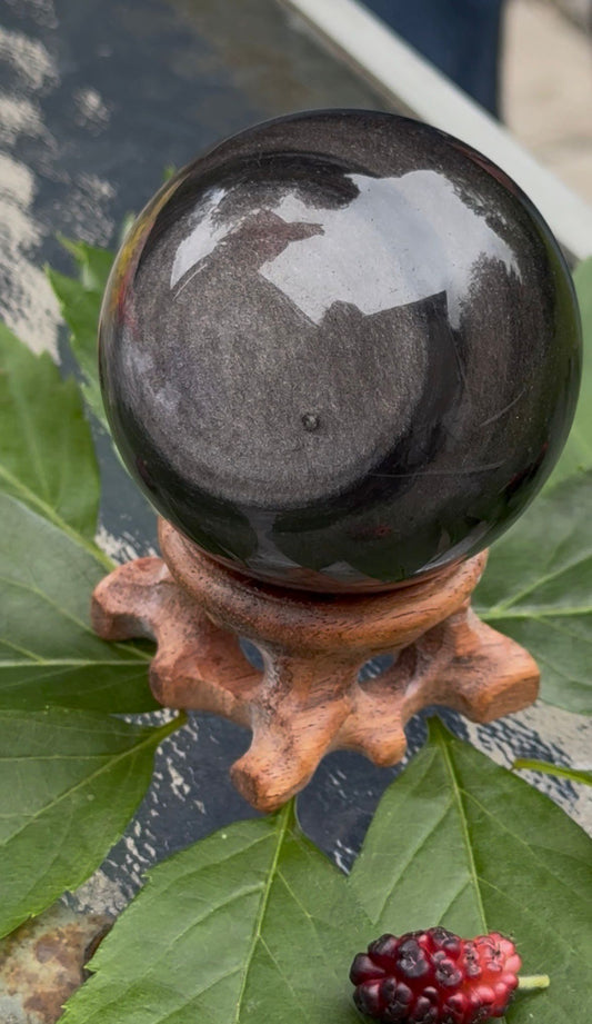 Polished obsidian globe displaying natural volcanic glass characteristics