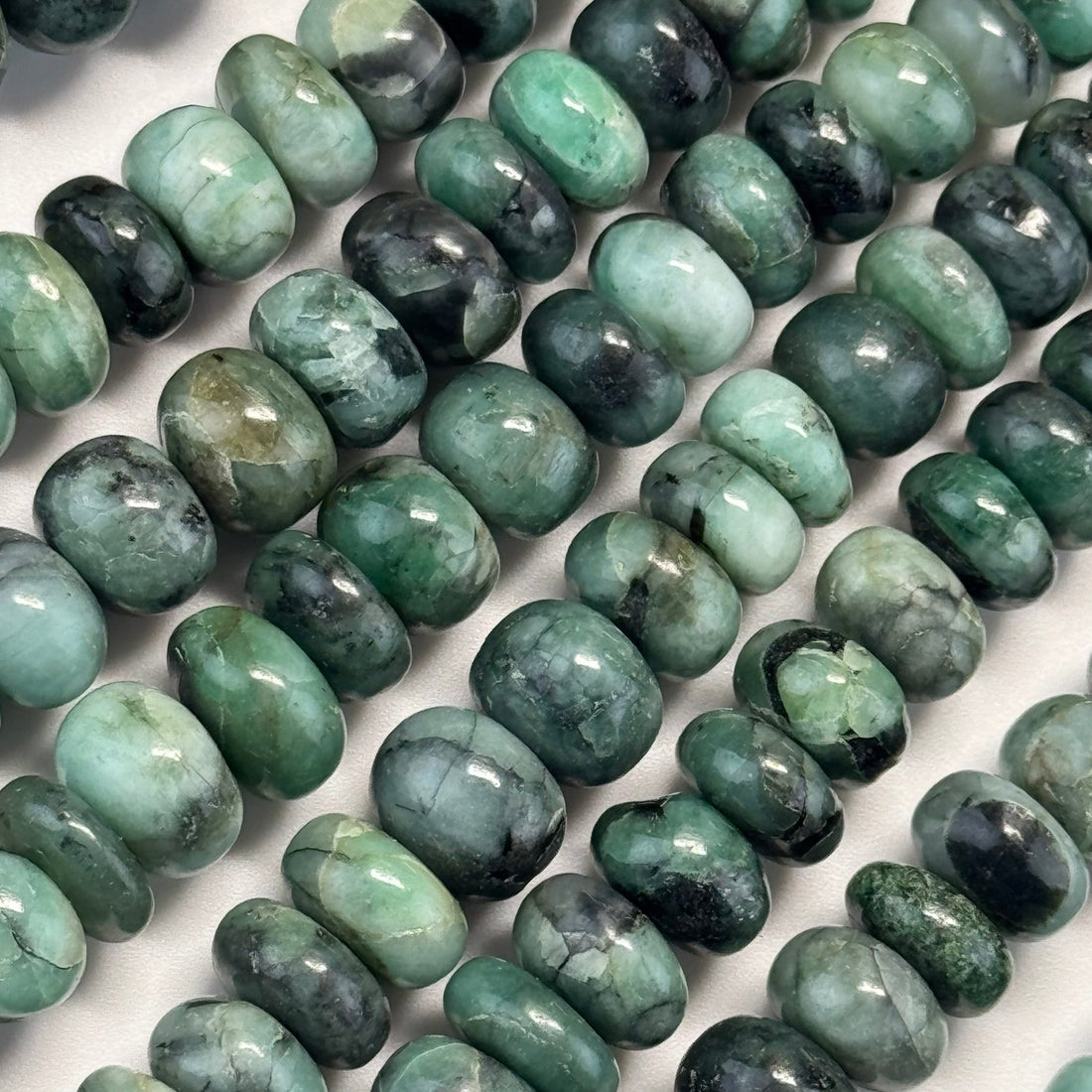 Natural green emerald crystals and cut emerald gemstones showing characteristic color and natural inclusions.